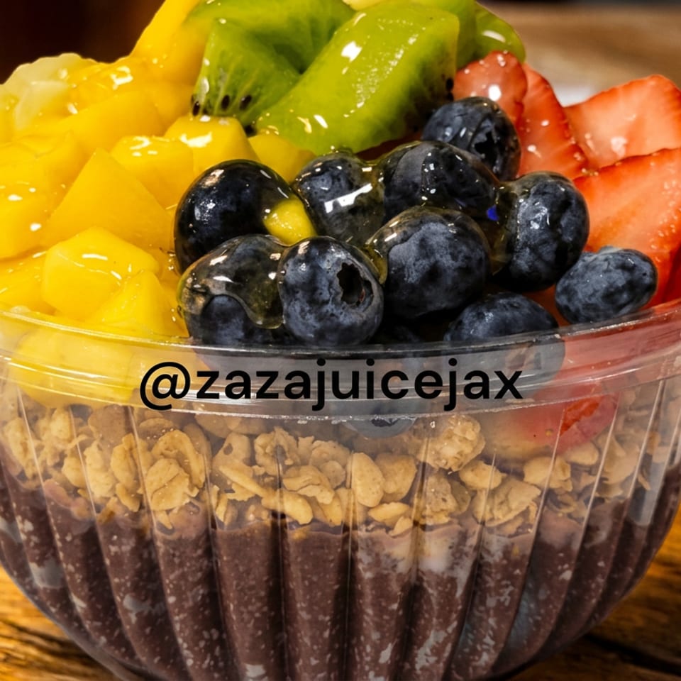 Layered fruit parfait with granola and chocolate pudding, topped with blueberries, strawberries, kiwi, and mango in a clear cup.